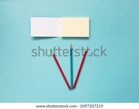 Blank note and color pencil on blue background