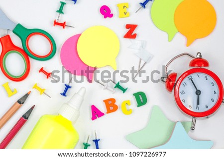 School supplies on white background. alarm clock, note paper, scissors, pencils, buttons, letters on white table