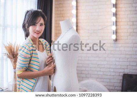 Happy young Asian woman fashion designer working in the studio