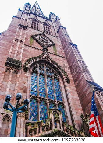 Trinity Church with American flag. Confession Episcopal Church located at the intersection of Wall Street and Broadway in the Financial District in Manhattan, New York, United States USA