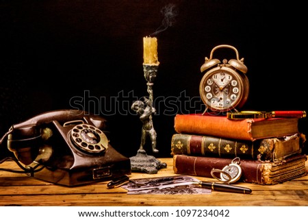 old still life books , alarm cloak , old analog phone and candle