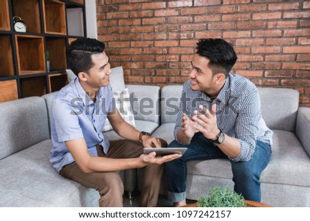 Happy young businessman using modern technology while they discuss about something