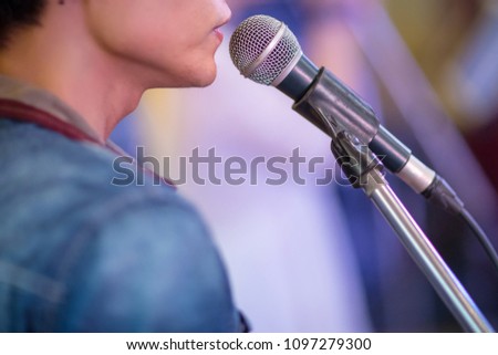 singer and microphone. Close up image of man singing to a microphone. Singer in front of a microphone.