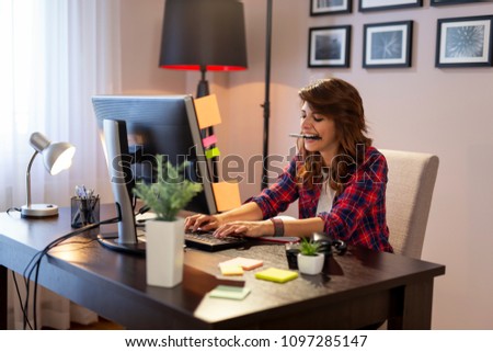 Young female IT specialist working in a home office, typing on a keyboard