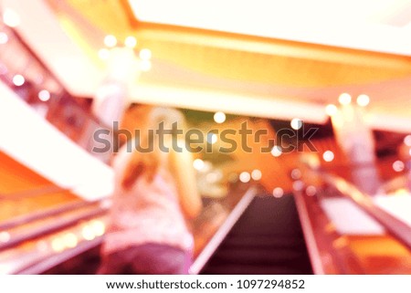 Blurred hall of shopping mall with customers as background.
