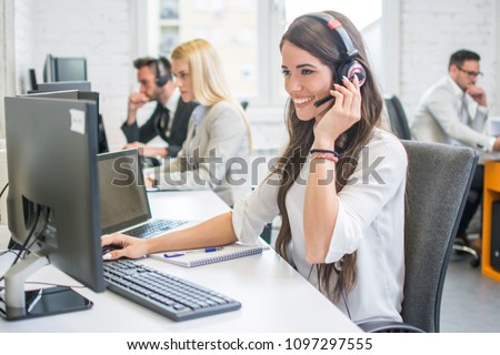 Friendly smiling woman call center operator with headset using computer at office Royalty-Free Stock Photo #1097297555