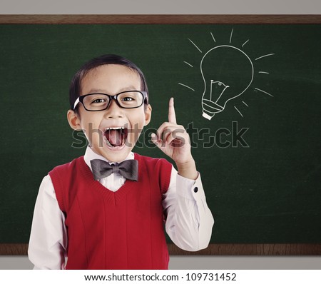 Portrait of male elementary school student with lightbulb picture on blackboard Royalty-Free Stock Photo #109731452