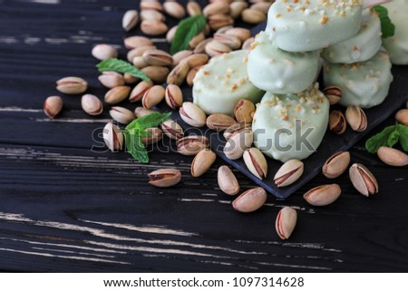 Pistachio ice crem popsicles and pistachio nuts on the black wooden background. Horizontal. Close-up.