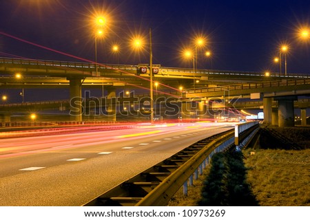 Cars, racing past a huge highway junction at night