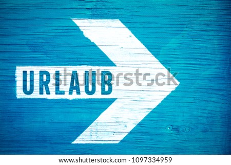 Urlaub (in German language, Holiday or Vacation) text sign written on a white directional arrow on a blue wooden signboard. Concept for tropical beach vacation and summer holiday travel.