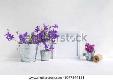 Mockup with a white frame and summer flowers in a metal bucket on a light background