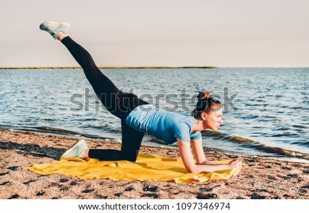 Young healthy woman doing yoga exercises at the beach