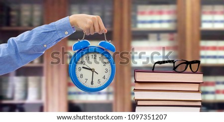 hand with watch in the library with books on shelves