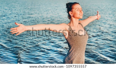 woman open arms under the sunrise at seaside 