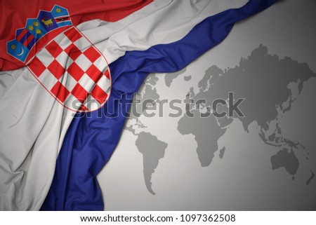 waving colorful national flag of croatia on a gray world map background.
