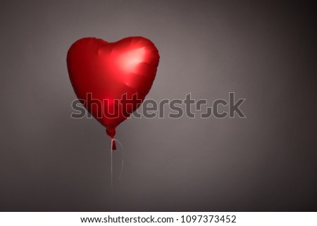 Red ball in the form of a heart on a gray background in the studio