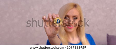 golden bitcoin in the hand of a beautiful blonde girl in blue dress