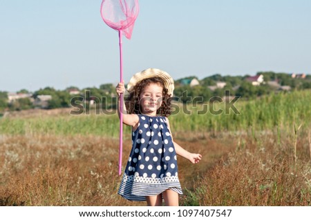 Beautiful curly girl in a hat chasing butterflies