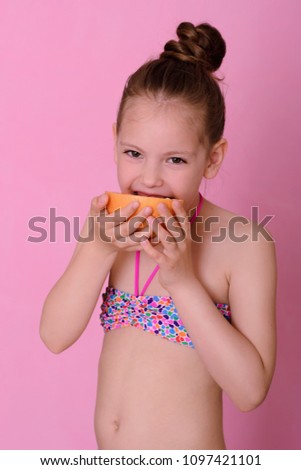 Caucasian beautiful little girl with grapefruit on a pink background.Child with oranges.