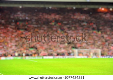 Blurred background of football stadium and soccer fans in match day on beautiful green field with sport light at the stadium.Sports,Athlete,People Concept.Anfield,Liverpool Royalty-Free Stock Photo #1097424251