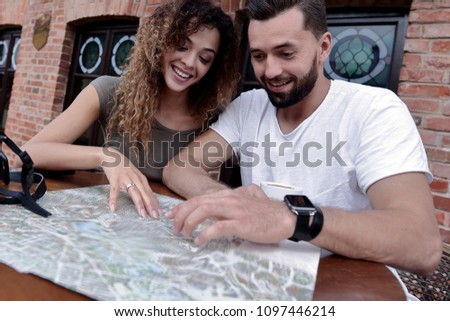 Couple in an outdoor cafe using map and planning itinerary