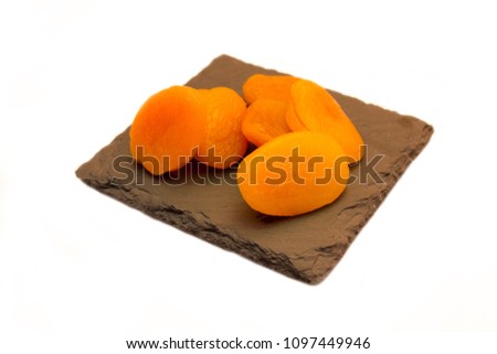 Pitted apricots on slate tray on a white background
