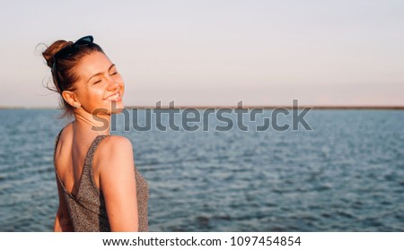 
beautiful young girl smiling with eyes closed against the sea, with copy space for your text