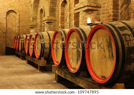 Wine barrels and bottles in a vineyard cellar with a lighting candle. The picture was taken in Csopak, Balaton, Hungary