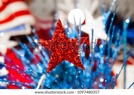 Festive holiday background with blurred flag in background and glitter star and decorative bokeh elements in foreground - red white and blue