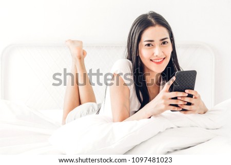Happy woman relaxing and using smartphone on the bed at home.woman checking social apps with smartphone