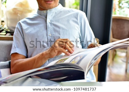 Man choosing food menu in restaurant, hand touching big size of menu book, selective focus blurred background, enjoying with Thai food concept  