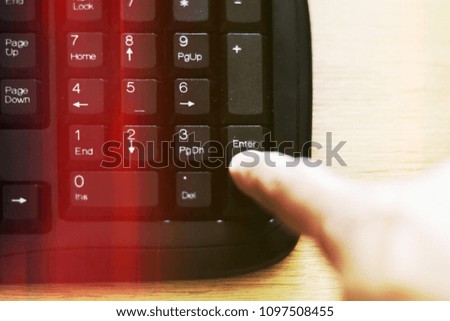 Selective focus Finger push on enter button of black computer keyboard with red light beam for illustration technology or communication concept.