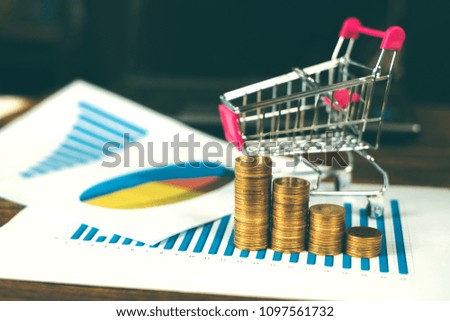 Step of coins stacks with trolley and notebook laptop computer and financial graph on paper on working table, business planning vision and finance analysis concept idea. and copy space for add text.