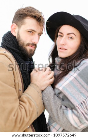 Portrait of man with beard and woman holding hands and wearing scarf and hat in white background. Concept of feelings and romantic love, winter photo session.