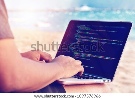 A programmer typing source codes at the beach on a sunny summer day. Studying, Working, Technology, Freelance Work Concept. Royalty-Free Stock Photo #1097576966