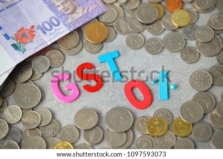 Alphabet "GST 0%" with money and coins on desk, top view.