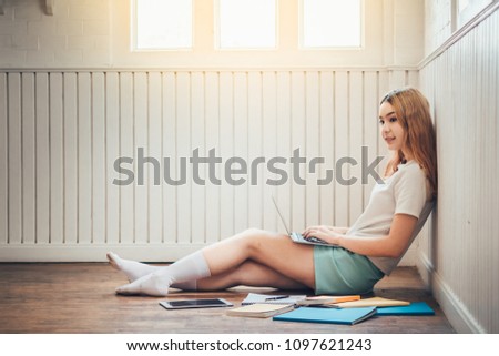 Education,Beautiful young student reading a book at library with book,clock and laptop on wood table, soft and blur concept.