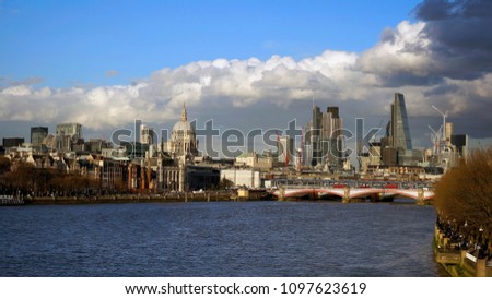 London skyline from Waterloo Bridge. Blackfriars Bridge, River Thames, and skyscrapers present, clouds over blue sky shows dramatic atmosphere