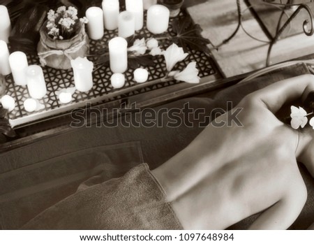 Massage of woman in spa salon. Girl on candles background in therapy room. Luxary interior in oriental therapy salon. Female have relax after sport. Black and white top view of photo.