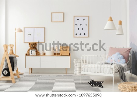 Blue pillow on white bed in scandi kid's bedroom interior with mockup of empty poster Royalty-Free Stock Photo #1097655098