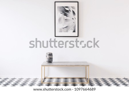 Minimalist black and white apartment interior for an artist with a luxurious golden bench and a framed picture on an empty wall