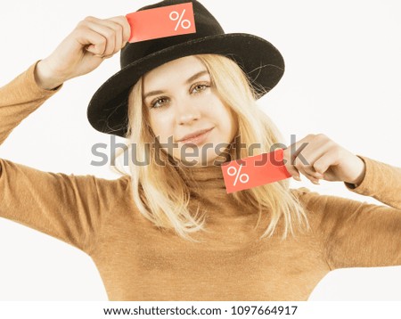 Woman in hat showing tag with shopping sale percentage sign enjoying cheap clothing. Female wearing stylish outfit.
