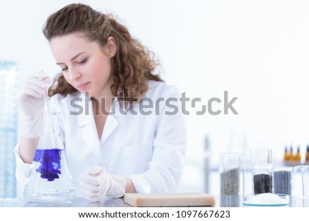 Chemist pouring substance into a flask with solution in the laboratory