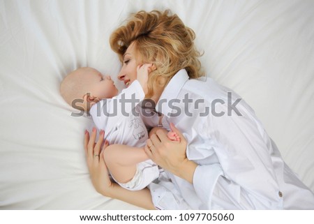 Family portrait of mother and baby in white bed. The view from t