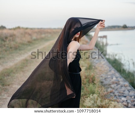 A woman in a dark dress and a transparent veil