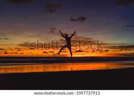 people on the shore of the ocean at sunset. man jumps against the backdrop of the setting sun.