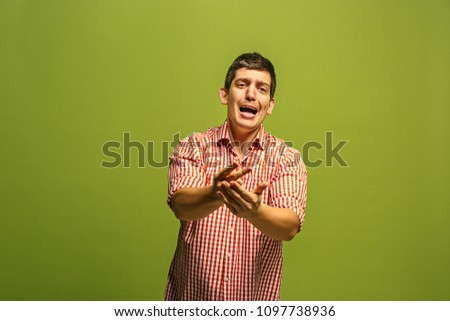 Argue, arguing concept. Funny male half-length portrait isolated on green studio backgroud. Young emotional surprised man looking at camera. Human emotions, facial expression concept. Front view