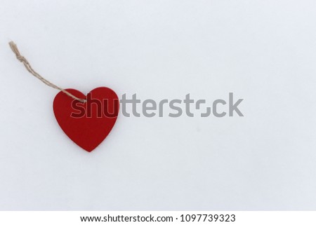 Red wooden heart on white snow background with copy space. Love and romance concept. Valentine romantic symbol. Decorative heart. Frozen heart. New Year tree toy. Lonely heart and unhappy love concept