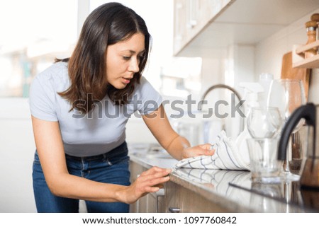 Young woman housewife cleaning furniture at  kitchen at home interior


