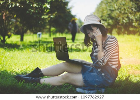 beautiful Asia woman teen,girl using computer notebook in durian fruit  garden learning with fun and happy on holiday.